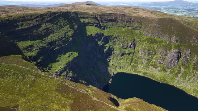 Dramatic aerial of Coumshingaun corrie lake beneath towering cliffs, Ireland