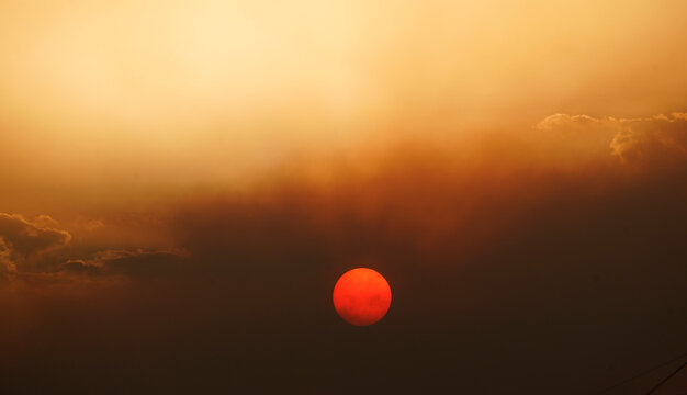 El Sol con manchas solares al atardecer entre nubes y polvo en suspensi&oacute;n de humo por incendios en Espa&ntilde;a
