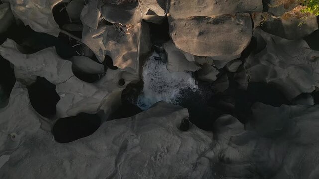 Quartzite waterfall of the Sao Miguel River cascades into a deep plunge pool at Vale da Lua, Chapada dos Veadeiros National Park, Alto Paraiso de Goias, Goias, Brazil, top-down drone ascent.