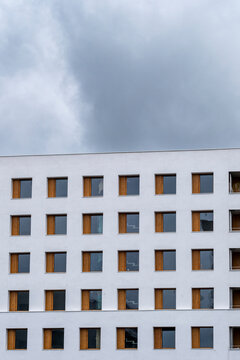 Under a brooding overcast, a white facade rises into clouds as windows establish the grid, and repetition defines the minimal building as modern architecture