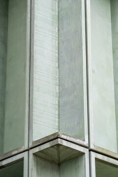 Within a restrained crop, a green surface carries weathered texture toward a sharp corner, where the vertical facade turns minimal architecture into quiet detail