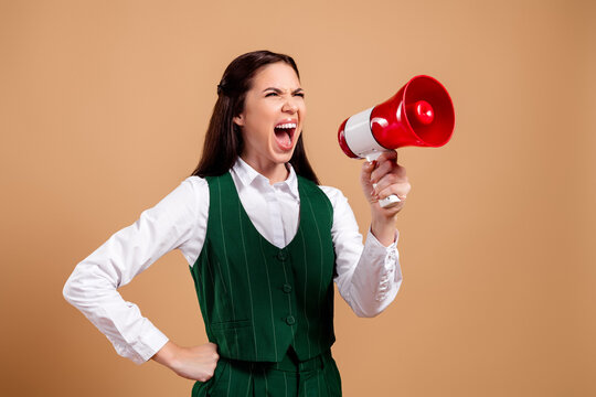 Businesswoman shouting through a red megaphone for announcement and empowerment, vocal leadership and communication concept in studio portrait