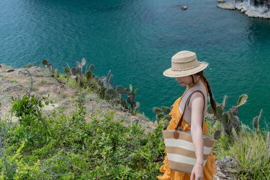 Woman looking down from grassy cliff edge, Hon Yen, Dak Lak, Vietnam