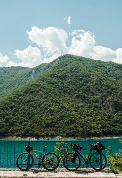 Two loaded gravel bicycles stand beside the bridge overlooking Piva Lake in Montenegro. The mountain reservoir provides a perfect backdrop for a bikepacking adventure