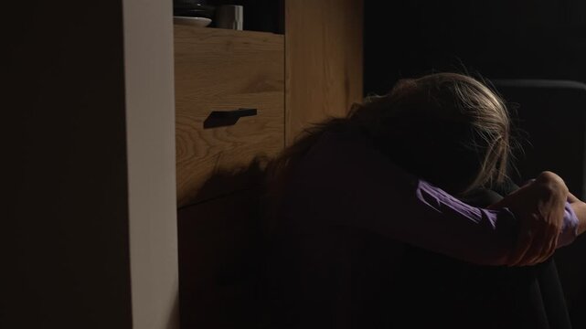 Desperate woman crying in darkness hiding her face.