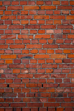 Textured red brick wall with varying shades and mortar joints, ideal for backgrounds and designs