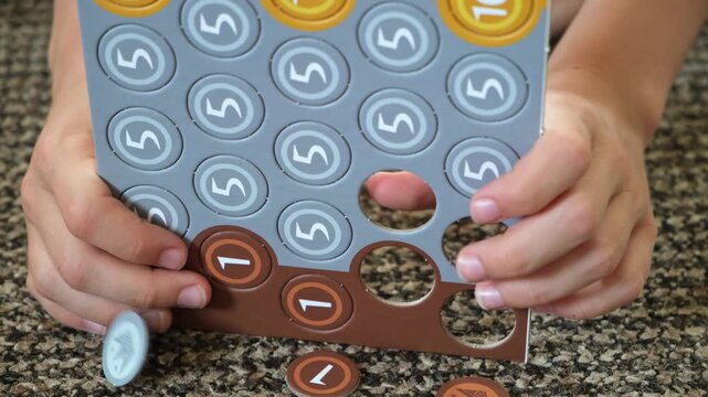 Child hands pressing out cardboard game tokens with one, five and ten nominal value. Numbers toys coins. Board game components, hobby activities, early development. High quality 4k footage.