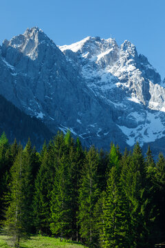 Travel landscape of Zugspitze Alps in Bavaria Germany, scenic summer nature panorama with forest, snow mountains peak. Alpine landscape