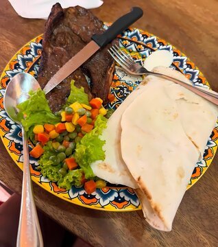 Grilled Beef Steak with Fresh Salad and Flatbread on Decorative Ceramic Plate