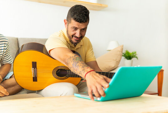 Man learning guitar online using a laptop