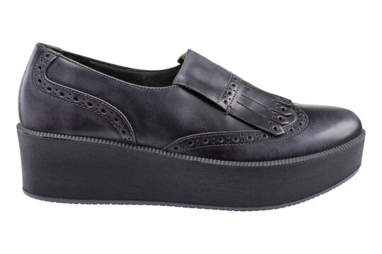 Women black leather kiltie platform loafers isolated on white background. Casual brogue creepers shoes with fringe, side view.