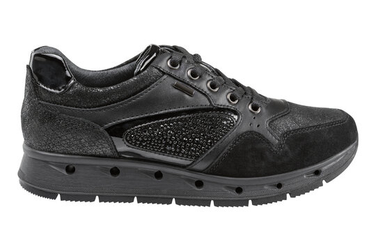 Women black mixed-media fashion sneaker isolated on white background. Casual running shoe with suede, patent leather and rhinestones, side view.