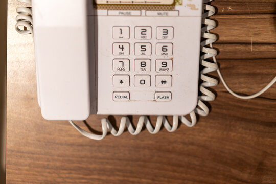White landline telephone with numeric keypad on wooden table