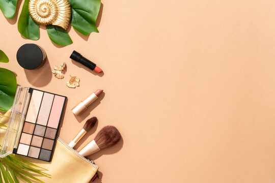 Summer make up background. Shadow palette, lipstick, serum bottle with palm leaves.
