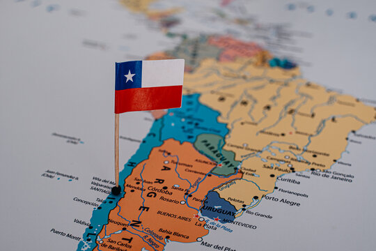 Close-up of a tiny Chilean flag pushpin marking a specific location on a physical map, conceptualizing travel, national identity, and geopolitics in South America.