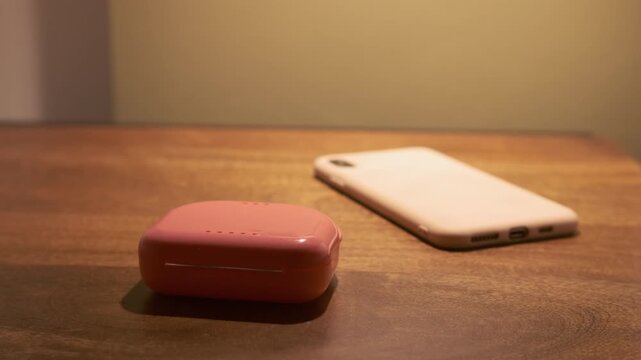 Crop hand of woman picking transparent teeth retainer from pink case kept besides smartphone on side table in dark bedroom