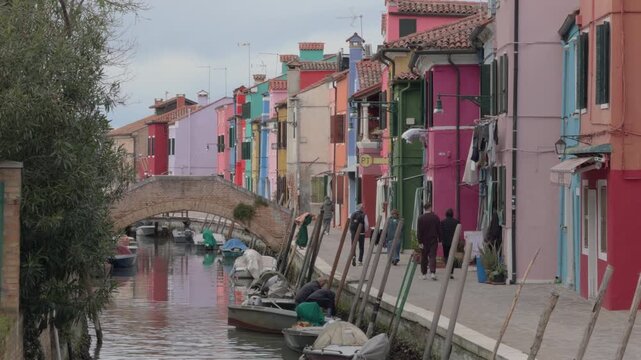 Quiet Burano Canal With Colorful Houses And Pedestrians