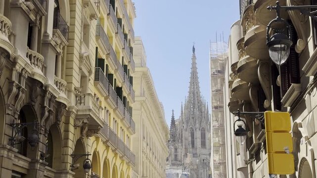Barcelona Cathedral spire seen from narrow Gothic Quarter street in summer