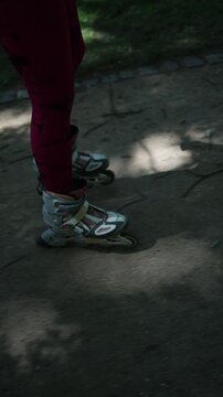 Vertical screen woman on roller skates has to ride over a rough dirt path because the park has no smooth paved route suitable for skating making her journey a much harder