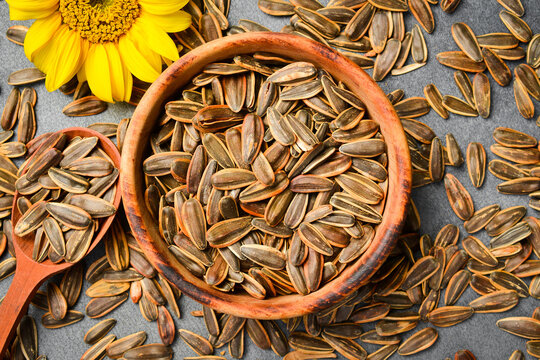 Roasted sunflower seeds with shells are in a rustic wooden plate. This natural snack is healthy and delicious. Ideal background for your food product presentation.