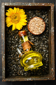 Sunflower oil in a glass decanter rests on raw seeds in a wooden box. Essential organic ingredient for healthy cooking. Perfect image for food design.
