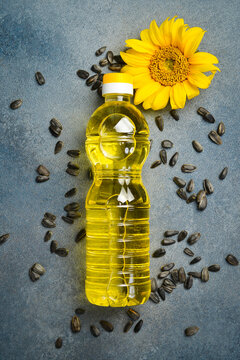 Natural sunflower oil bottle stands among raw seeds and yellow blossom. Pure vegetable product for cooking and salad dressing. Great background for organic food.
