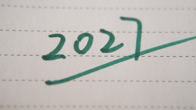 Close up of woman hand writes the number 2027 with a felt tip pen in a notebook. Concept of planning, motivation and setting goals for the coming year.