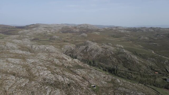 Smooth drone flyover across Serra da Freita highlighting unique granite formations and the raw beauty of this mountainous region, revealing natural textures, rocky plateaus, and scattered vegetation.