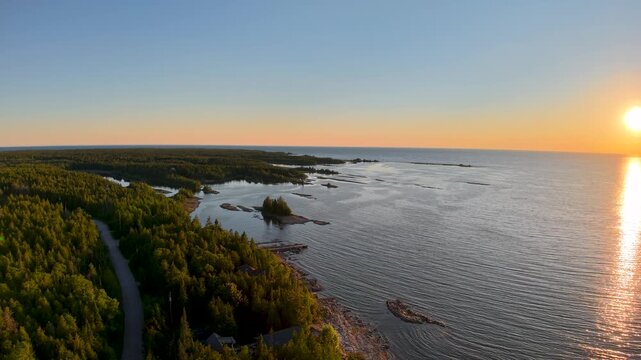 Golden sunset illuminates open water and forest edged coves along the Lake Huron coast