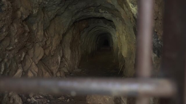 Mining cave entrance in the Sulcis Iglesiente region of Sardinia, Italy, showing the historic mine opening, rocky terrain and surrounding natural landscape