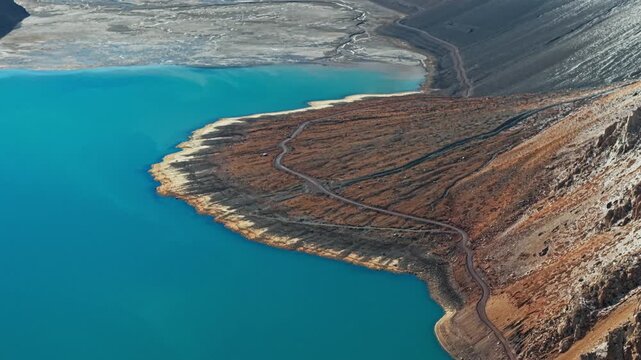 Aerial flying over turquoise waters of El Yeso reservoir, Chile. Pan left