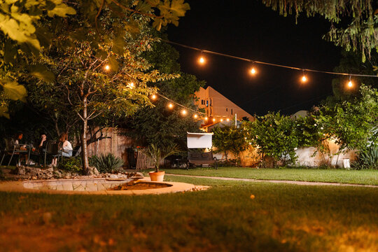 Friends enjoying backyard party at night with string lights