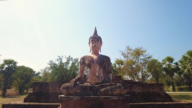 Small Buddha statue inside ancient ruins of Wat Maha That. UNESCO World Heritage Site, camera jib