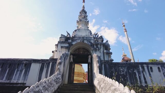 POV moving up ancient stone stairway to Buddhist temple entree in central Thailand