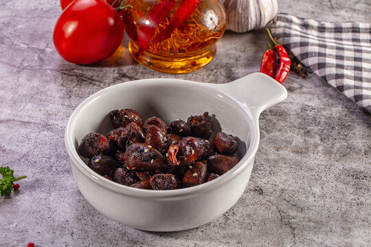 Spicy glazed chicken hearts in a ceramic bowl on a rustic table