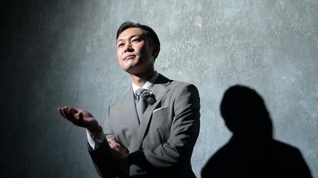 グレー背景で笑顔でプレゼンをする日本人男性