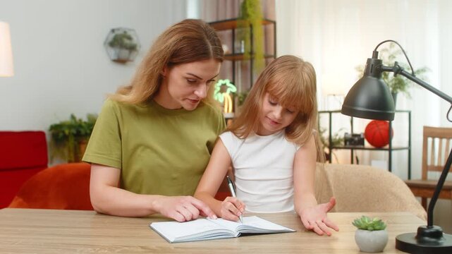 Mother and daughter at home check math answer use notebook and pen mark ticks say hooray feel proud. Woman and girl at table explain steps count sums check work learn rule practice focus steady pace
