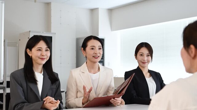 会議で笑顔を見せながら打ち合わせをする20代から40代の日本人ビジネスパーソン4人