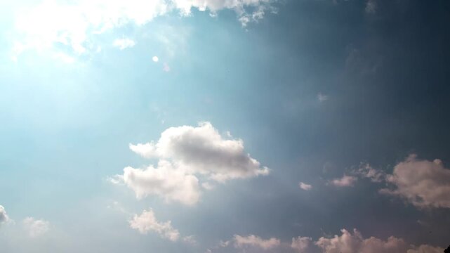 Time-lapse of dramatic cumulus clouds moving across a bright blue sky with sun rays breaking through
