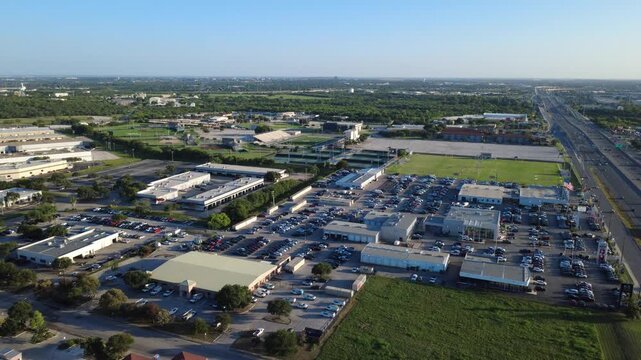 High angle perspective captures Northwest Loop 410 commercial sector in Alamo Downs Industrial Park near Bexar County sports fields. Vehicle inventory lots stretch alongside freeway lanes