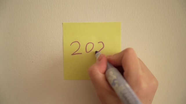 Hand writing with purple marker on post it note. New year 2027 concept