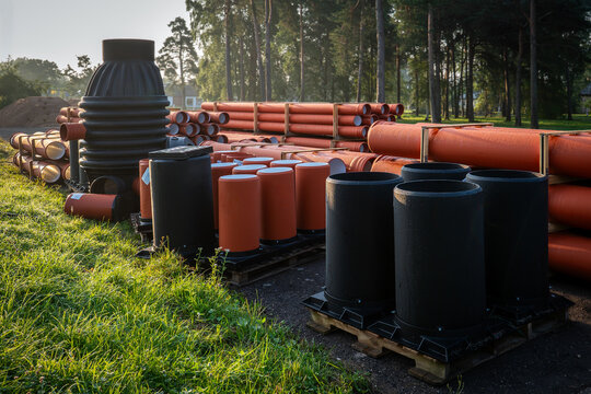 Drainage Pipes and Inspection Chambers Stored Beside a Sunlit Forest