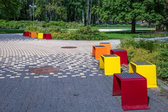 Colorful Modern Seats Line a Curved Walkway in Green Urban Park