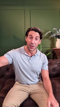 Confident male influencer sitting on a couch, speaking and gesturing directly to the camera, creating content for his online audience