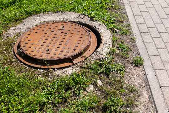 Displaced Metal Manhole Cover Creates Danger Beside a Public Sidewalk