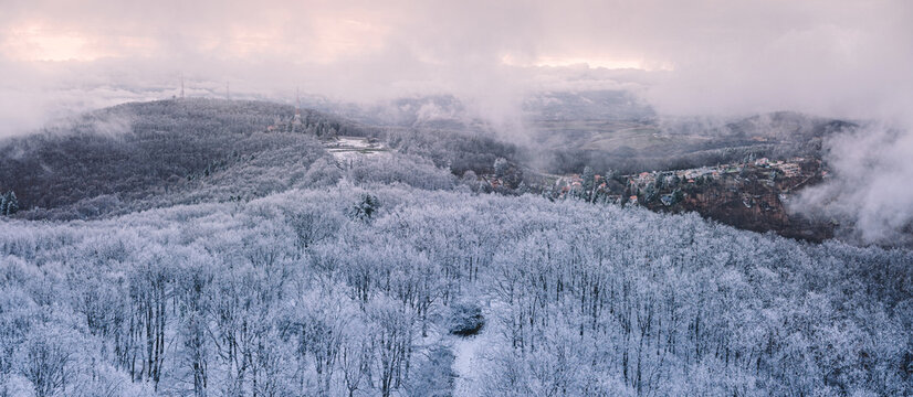 Panoramic aerial view of frost-covered forest hills shrouded in winter mist. Winter escape concept.