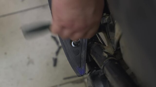 An engineer tightens a nut onto a bolt in a scooter's body.