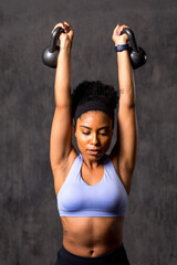 Fototapeta premium Focused woman lifting kettlebells powerfully.