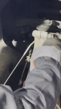 Mechanic uses brush to remove dust from front chassis elements. Technician cleans automobile part in area of upper ball joint in service center
