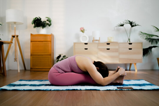 Mature female asian yoga home living room practice